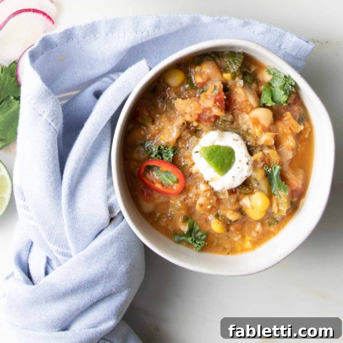 Hearty Vegan White Bean Chili 2 A steaming bowl of Vegan White Bean Chili garnished with fresh herbs and a lime wedge, ready to be enjoyed.