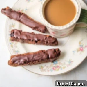 Plant-Based Biscotti Perfection 10 flowery china plate with three chocolate covered biscotti and a cup of coffee
