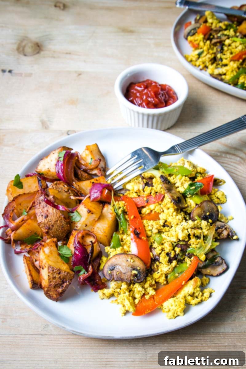 Golden Tofu Scramble 10 Large white plate with home fries and veggie scramble, showing a complete breakfast meal.