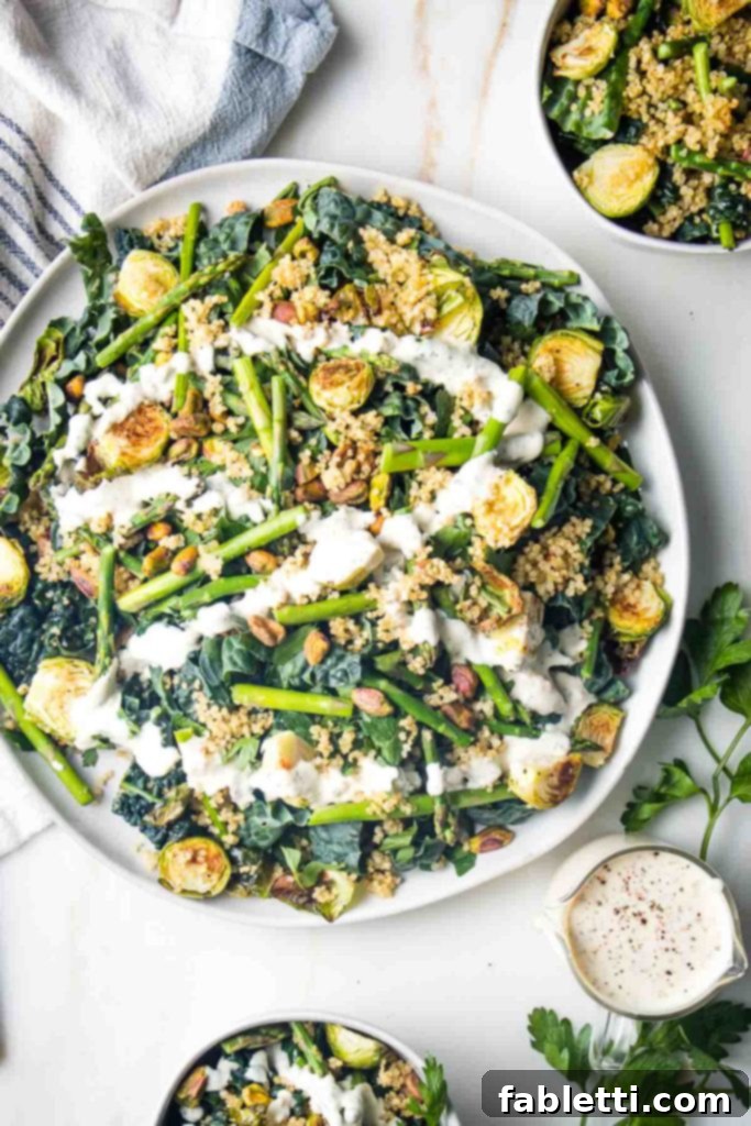 Golden Crisp Quinoa Salad with Silky Plant-Based Dressing 2 A composed salad featuring crisp quinoa, roasted vegetables, kale, and nuts, elegantly drizzled with a creamy dressing.