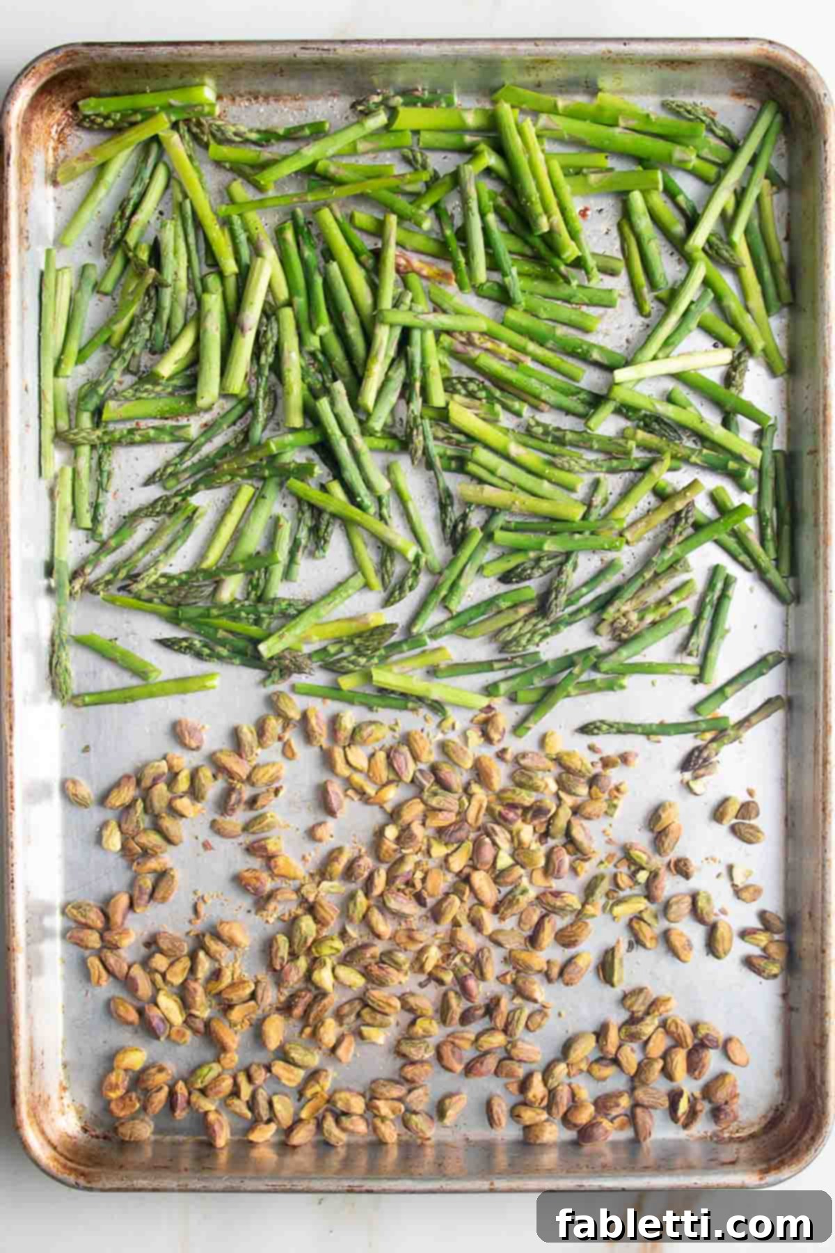 Golden Crisp Quinoa Salad with Silky Plant-Based Dressing 6 A large baking tray showing roasted asparagus pieces and pistachios, perfectly toasted and crunchy.