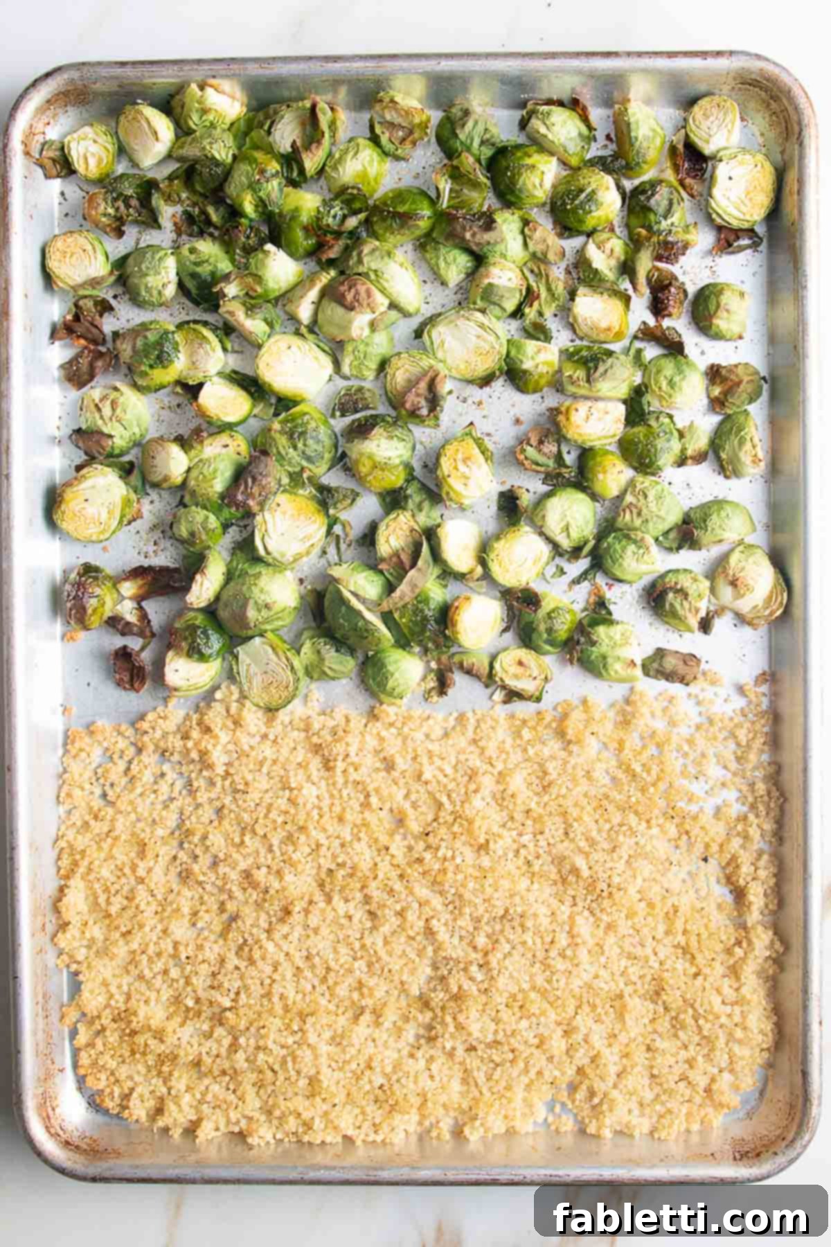 Golden Crisp Quinoa Salad with Silky Plant-Based Dressing 7 A large baking tray with roasted Brussels sprout halves and a pile of perfectly crisped quinoa, golden brown and crunchy.