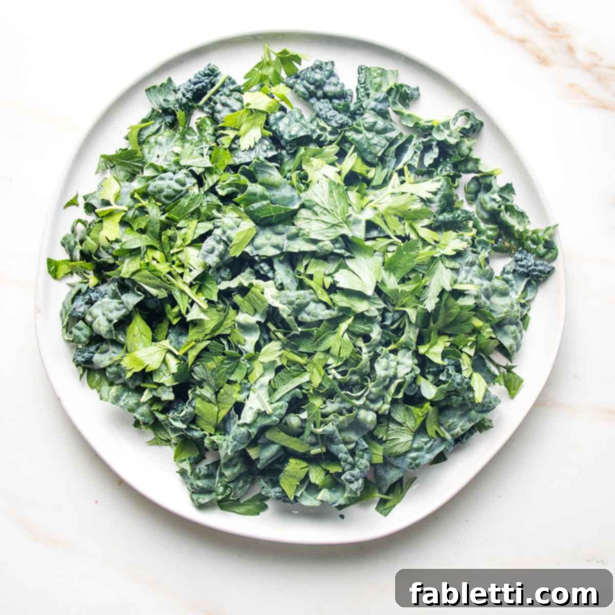 Golden Crisp Quinoa Salad with Silky Plant-Based Dressing 9 A large white plate filled with neatly chopped lacinato kale, ready for salad assembly.