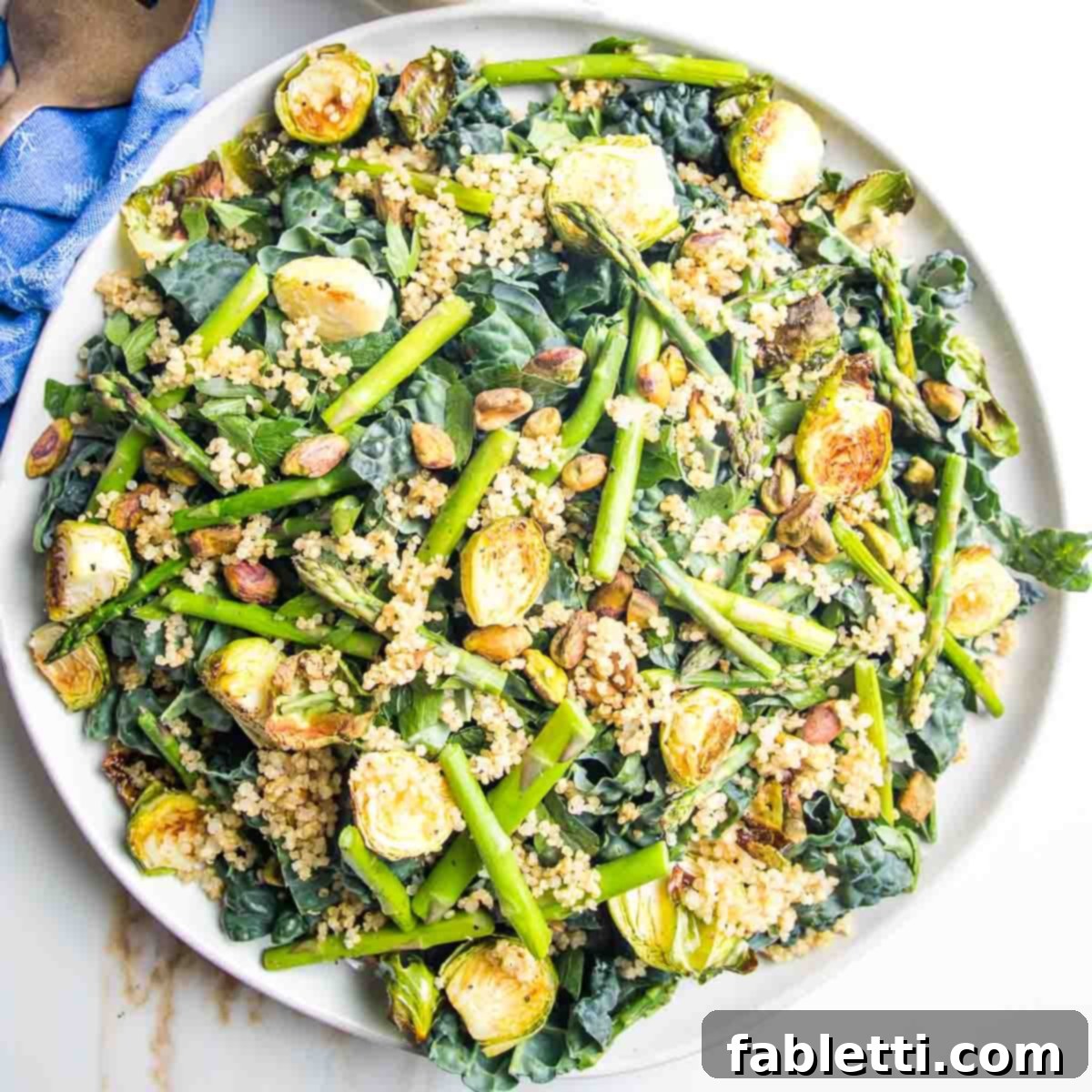 Golden Crisp Quinoa Salad with Silky Plant-Based Dressing 10 A large platter generously covered in a bed of greens, topped with a colorful array of roasted vegetables and crispy quinoa.