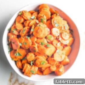 white bowl filed with spiced carrot rounds, sprinkled with chopped green parsley