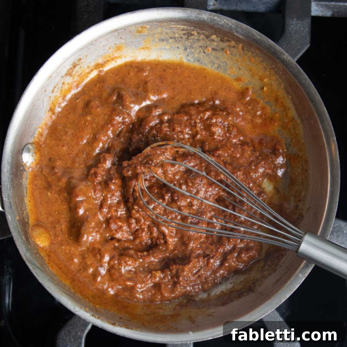 Whisking in some veggie stock to the tomato and spice mixture.