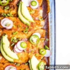 Hearty Plant-Based Enchilada Bake 13 Casserole Dish with enchiladas, garnished with avocado slices, jalapenos and radishes.