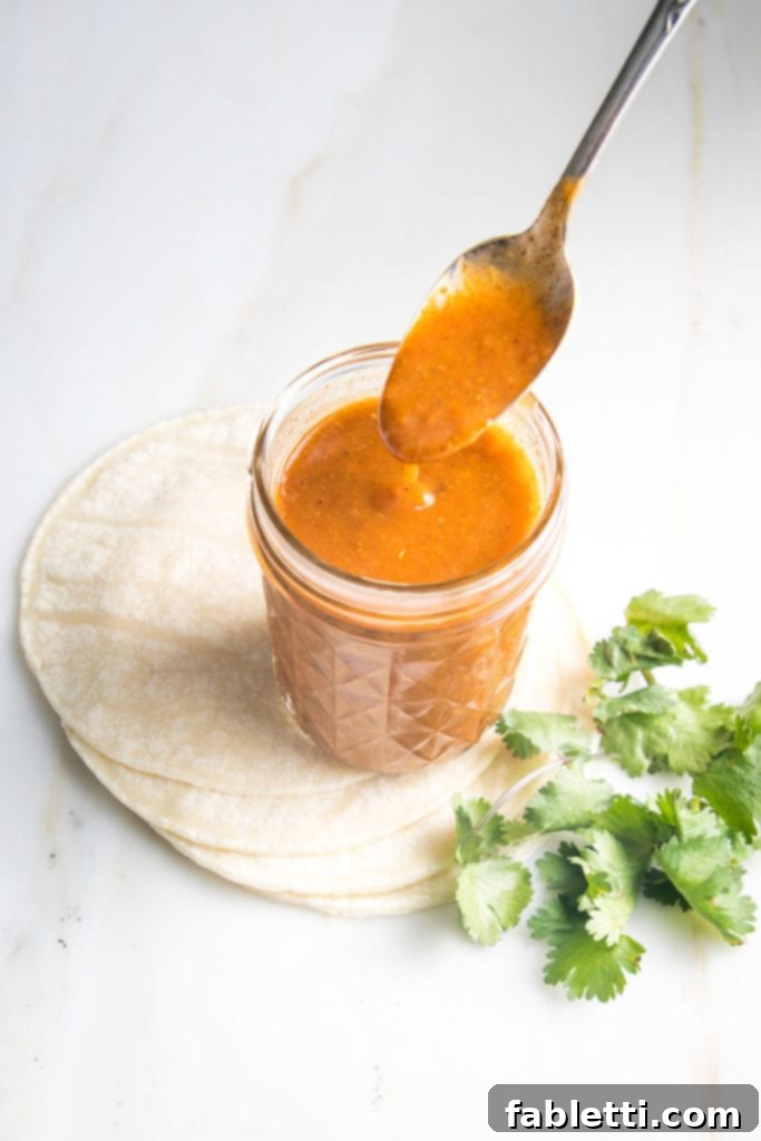 Hearty Plant-Based Enchilada Bake 6 Red Enchilada Sauce in a jar on top of tortillas with a side of cilantro