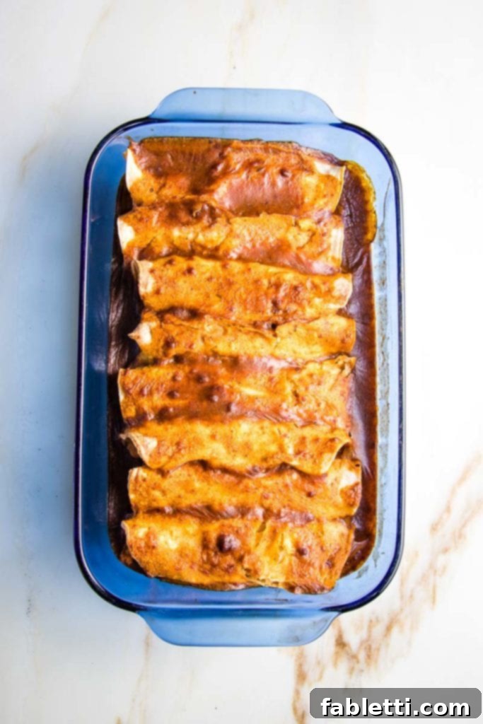 Hearty Plant-Based Enchilada Bake 10 enchilada casserole with red sauce, baked in a casserole dish.