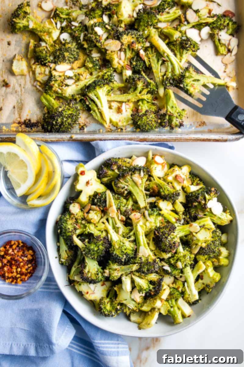 Spatula transferring roasted broccoli from sheet pan to a serving bowl, showcasing its golden crispiness.