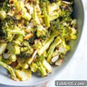 close up of a bowl of roasted broccoli with sliced almonds, perfectly golden and crispy