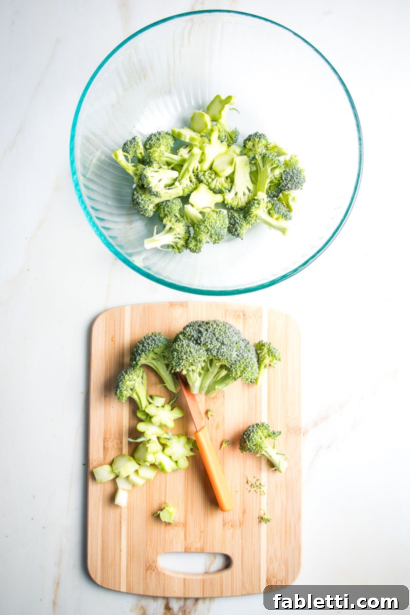 Trimming broccoli florets into bite sized pieces and placing them in a large mixing bowl with the sliced stems.