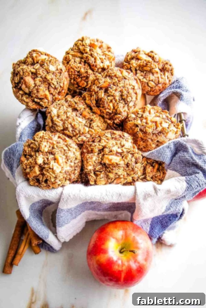 Basket of oatmeal apple muffins plus an apple and a few cinnamon sticks, evoking a warm, inviting feel.