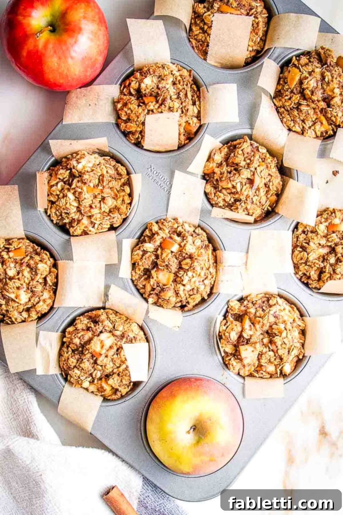 Chunks of apples baked into golden-brown oatmeal muffins in a tin, fresh from the oven.