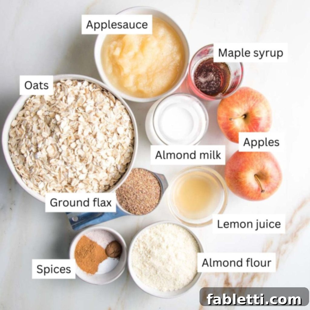 Labeled ingredients: applesauce, oats, almond milk, maple syrup, apples, spices, lemon juice and almond flour, neatly arranged for the recipe.
