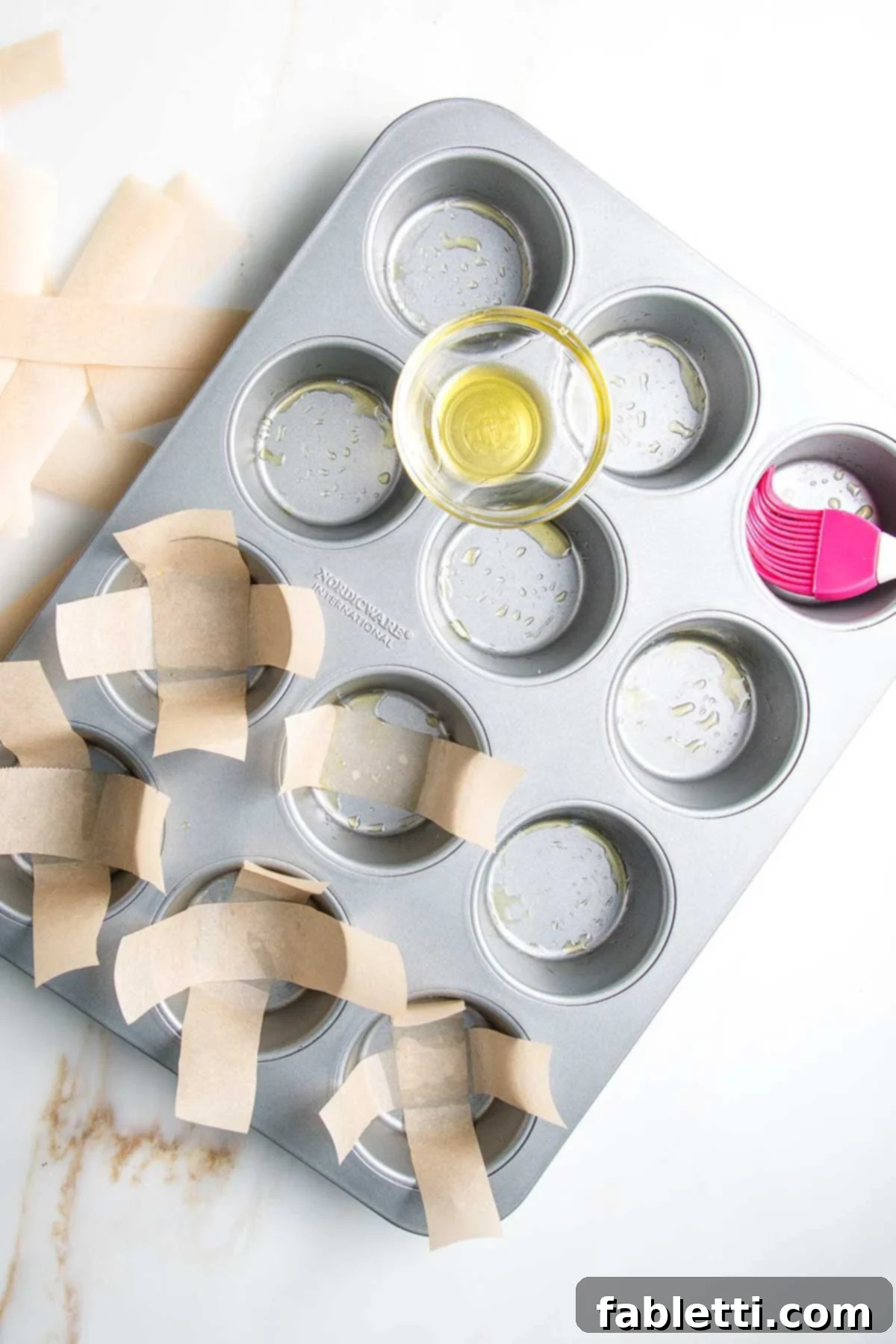 Muffin tin, brushed with oil and lined with strips of unbleached parchment paper in a criss-cross pattern.