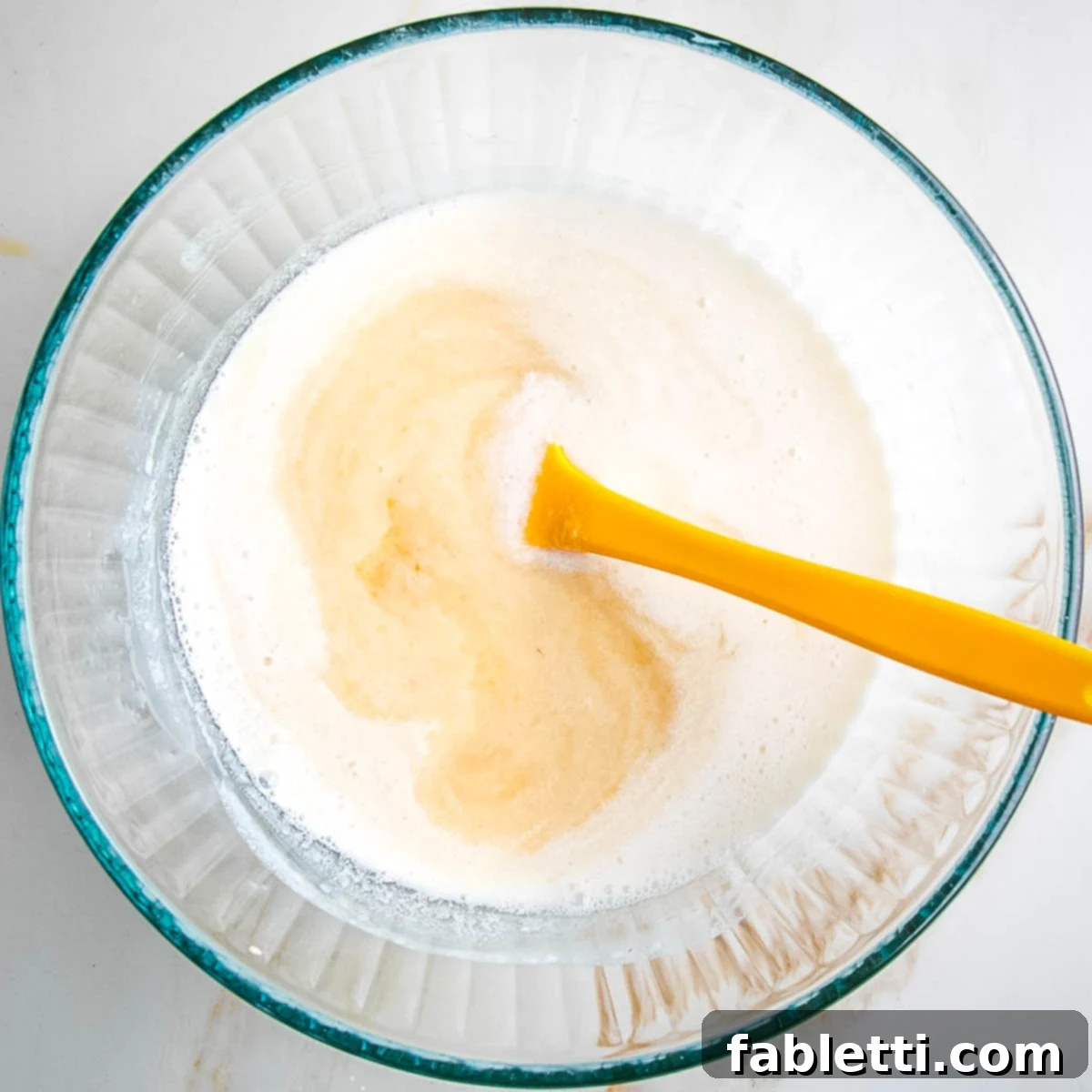 Mixing together wet ingredients for vegan apple oatmeal muffins in a bowl.