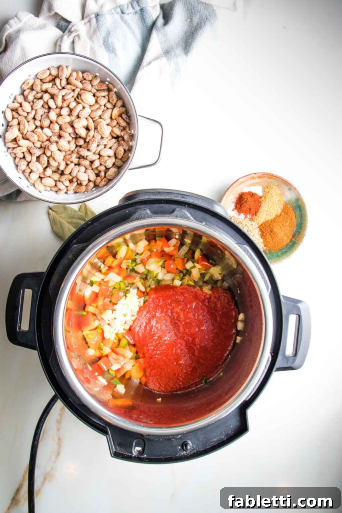 Easy Instant Pot Mexican Pinto Beans 8 Tomato sauce poured on top of sauteed veggies in an instant pot, plus a dish of spices and a bowl with soaking pinto beans.