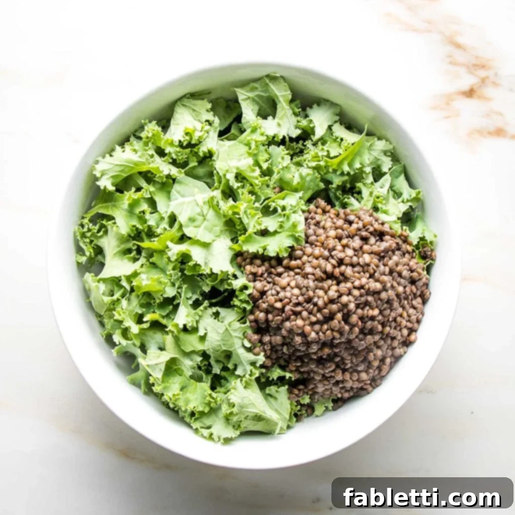 Vibrant Vegan Lentil Medley 7 A large white bowl filled with kale and a generous scoop of cooked black lentils.