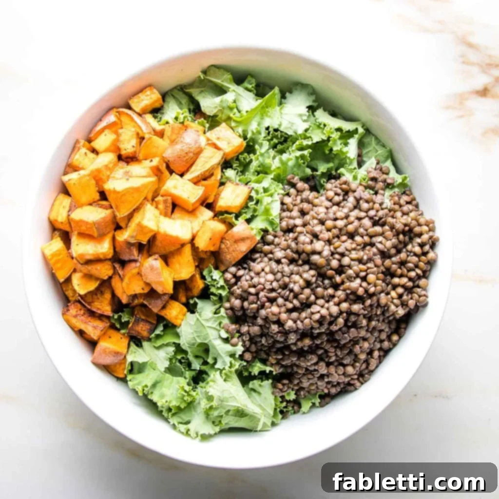 Vibrant Vegan Lentil Medley 8 A large white bowl brimming with kale, black lentils, and roasted sweet potato cubes.