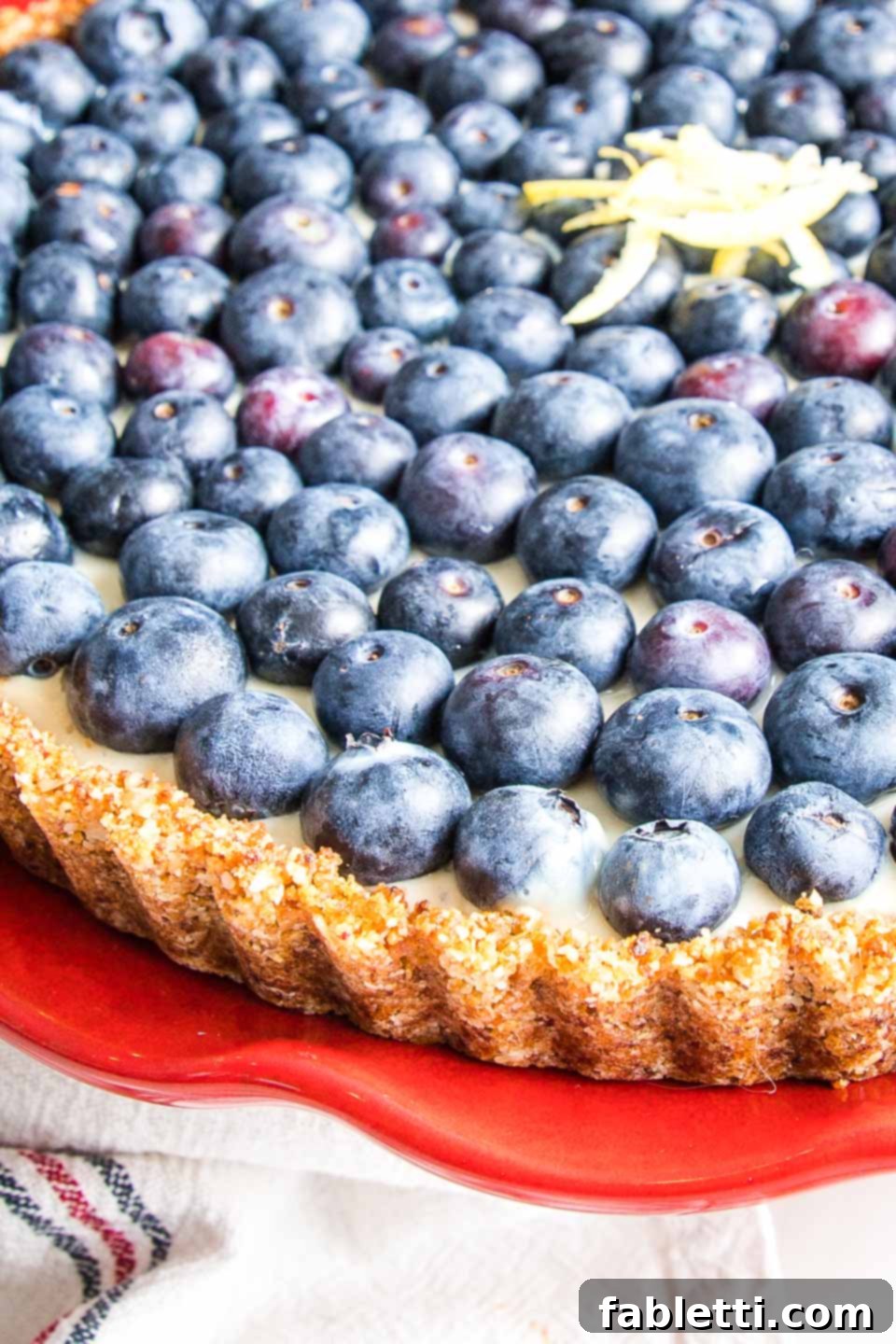 Homemade Blueberry Tart Perfection 4 A close-up, front view of the blueberry tart, highlighting its beautifully golden-brown crust, presented on a bright red cake stand.