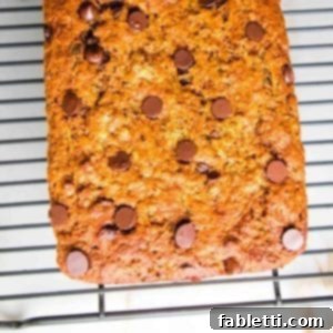 Wholesome Vegan Zucchini Bread Sweetened with Applesauce 12 Chocolate Chip Zucchini Bread cooling on a wire rack on a white countertop, showcasing its golden crust and delicious texture.