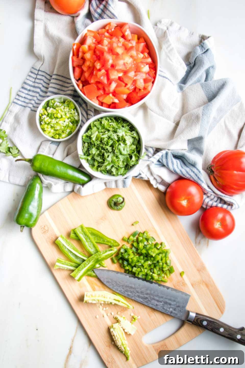 Vibrant Chunky Tomato Salsa 6 Fresh chopped tomatoes, cilantro and scallion for salsa, along with a cutting board with knife, showing how to remove the seeds and membranes from the jalapeno to chop.