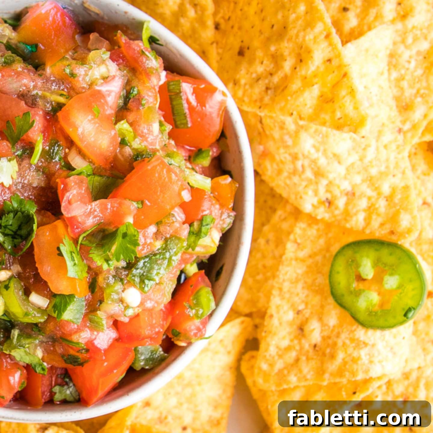 Vibrant Chunky Tomato Salsa 8 Fresh Tomatoes, Cilantro, Jalapenos and scallions chopped up for a homemade salsa, served with a side of corn chips.