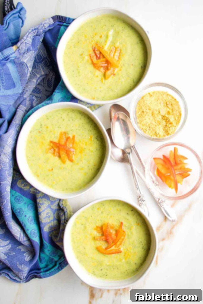 Velvety Zucchini Soup 2 Creamy green soup in bowls with red pepper garnish.