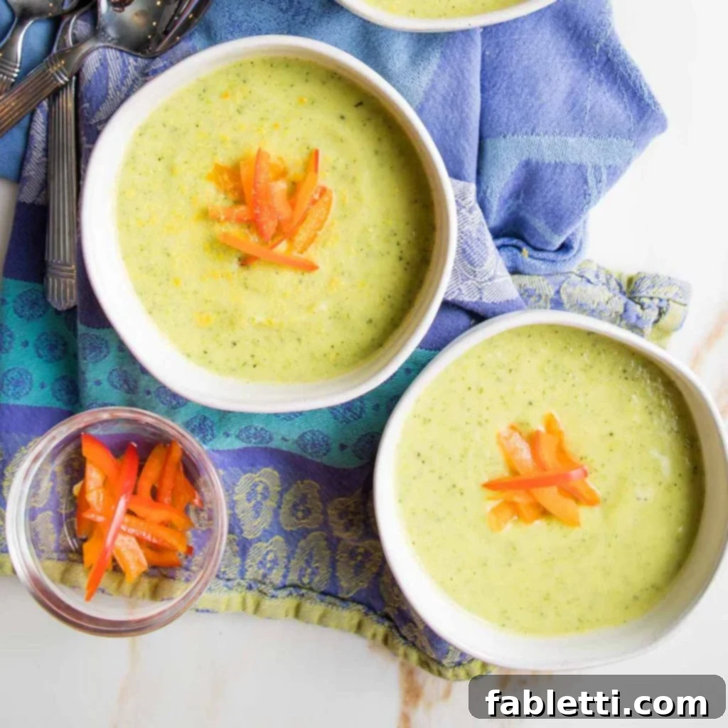 Velvety Zucchini Soup 11 Two bowls of creamy green soup, garnished with julienned red pepper slices.