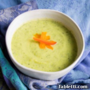 Velvety Zucchini Soup 12 Light green creamy soup with red pepper slices as garnish.