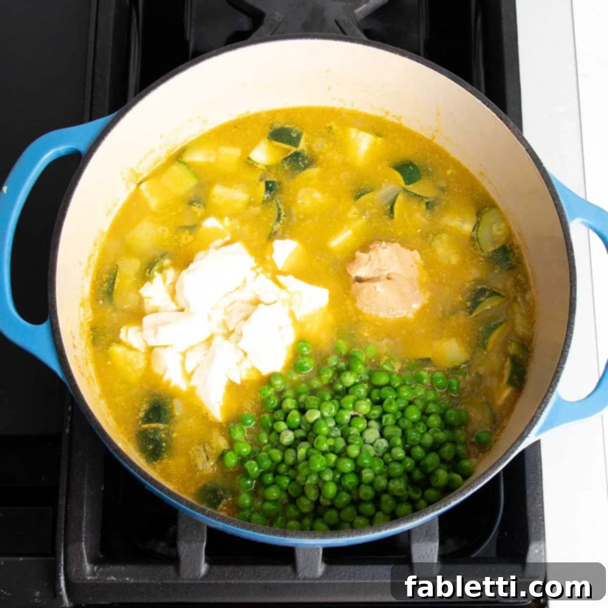 Velvety Zucchini Soup 9 Broth cooking in dutch oven with chunks of zucchini plus peas, tofu and miso.