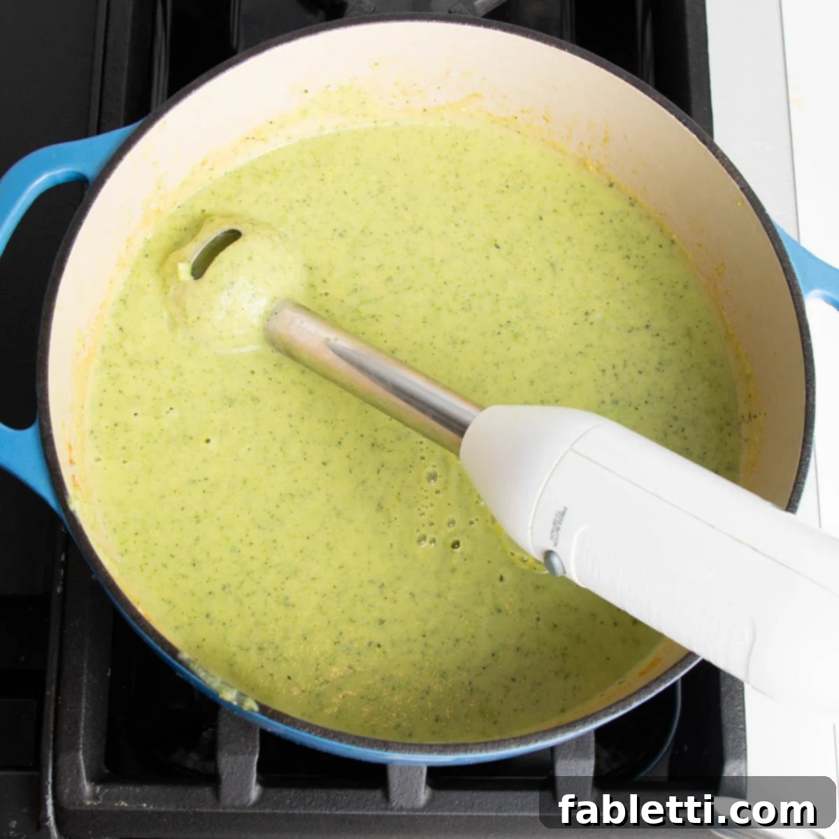 Velvety Zucchini Soup 10 Immersion blender in a dutch oven, pureeing light green soup.