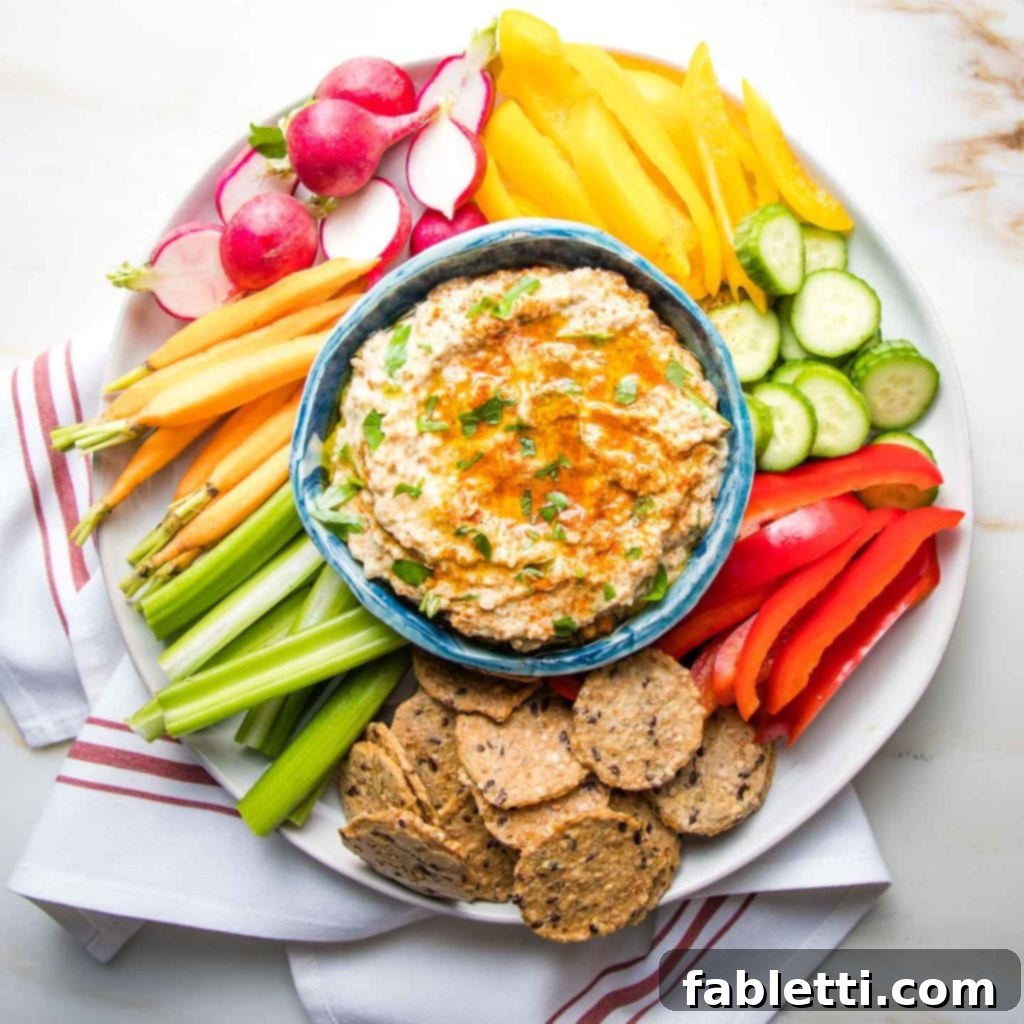 Velvety Roasted Garlic and Tahini Baba Ganoush 12 Colorful Crudites with a bowl of roasted eggplant dip in the center that is garnished with paprika and fresh parsley