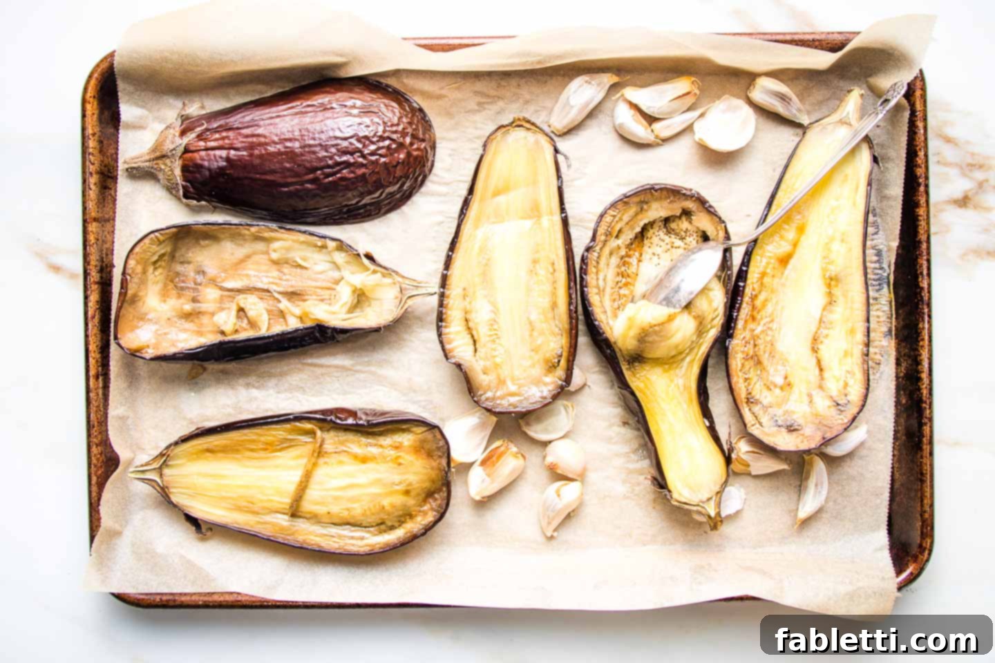 Velvety Roasted Garlic and Tahini Baba Ganoush 7 Scooping out the pulp of roasted eggplant with a spoon.