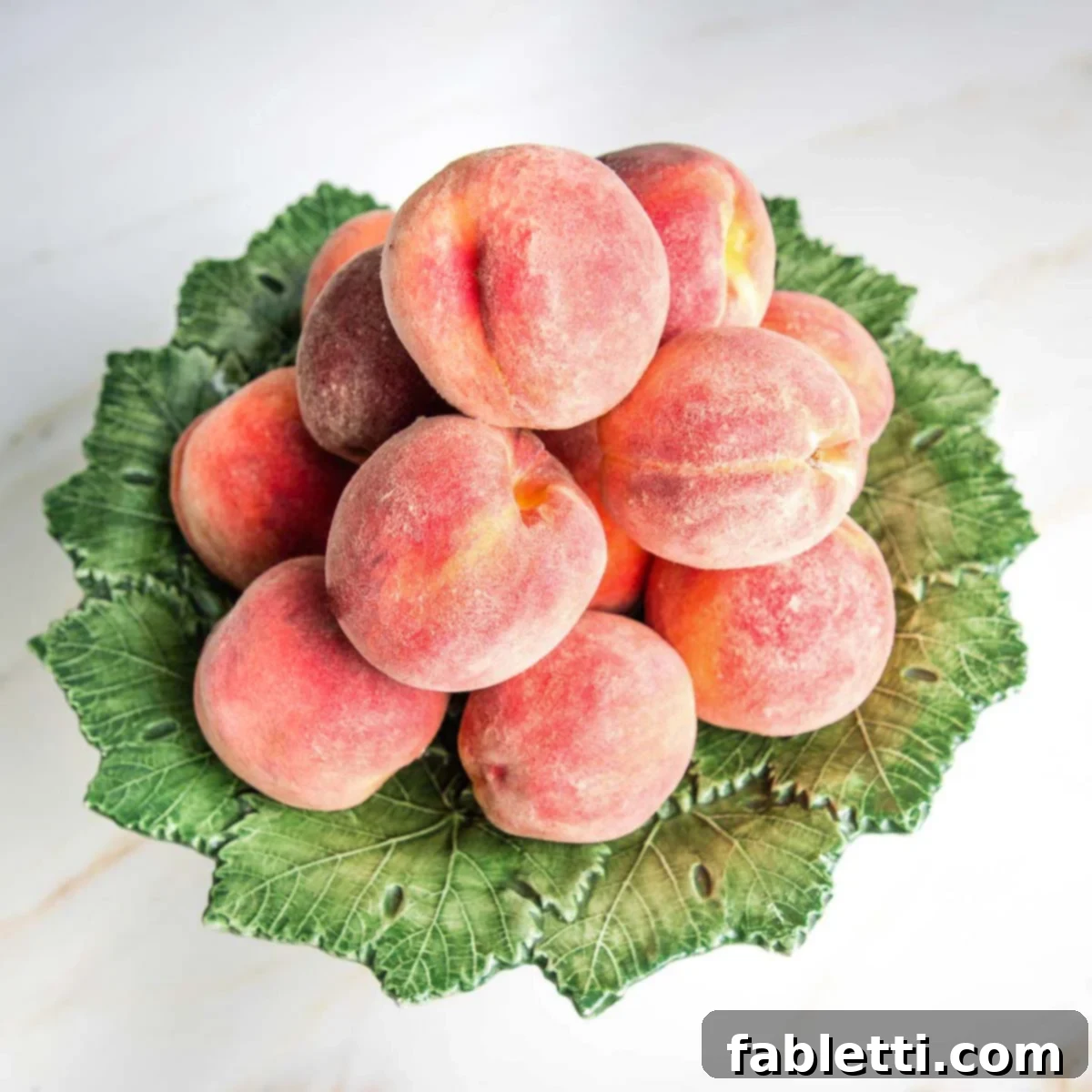 Pile of fresh, ripe peaches on a green leafy pedestal, ready for baking.