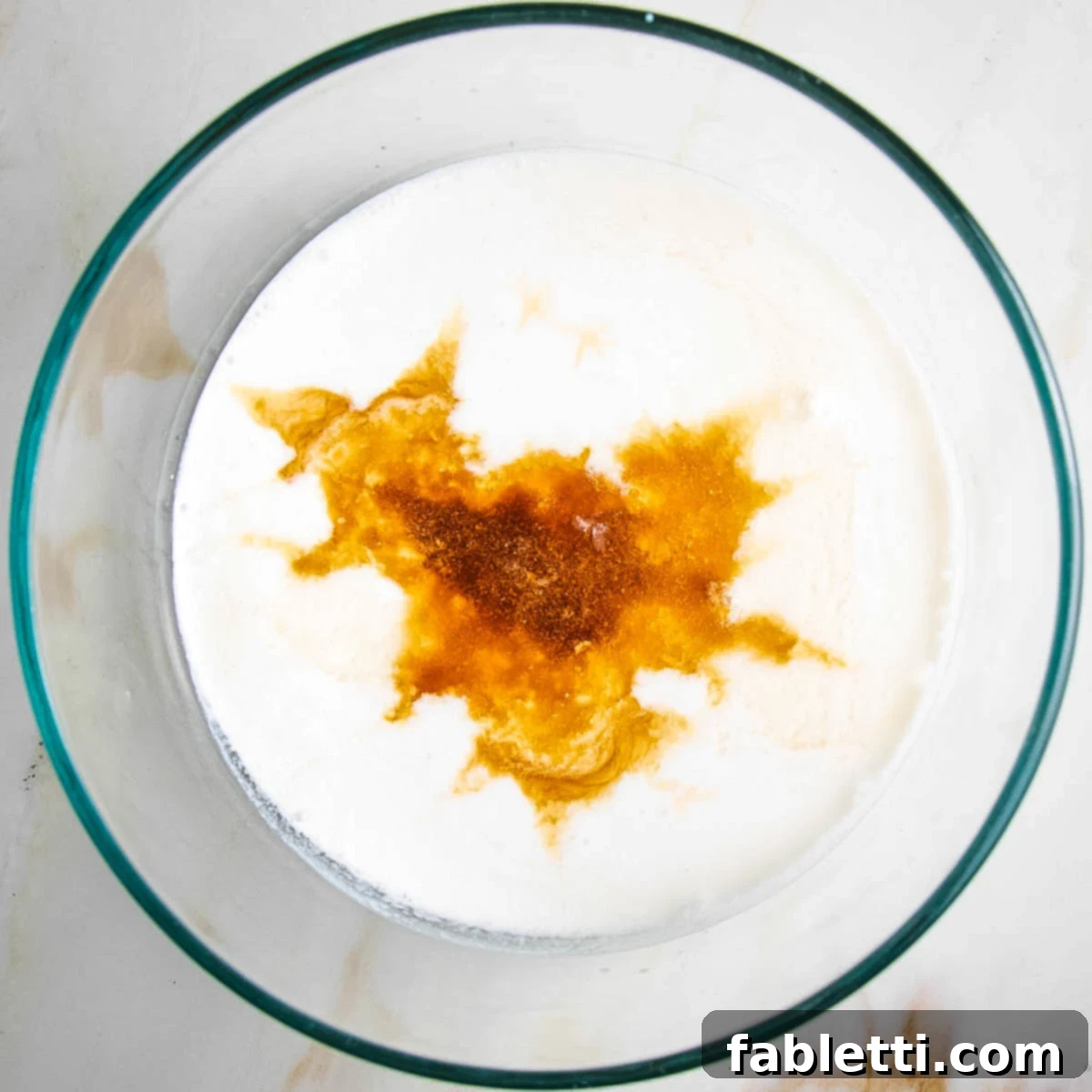 Almond milk, vanilla, and other wet ingredients for fruit cobbler topping measured out in a medium bowl.