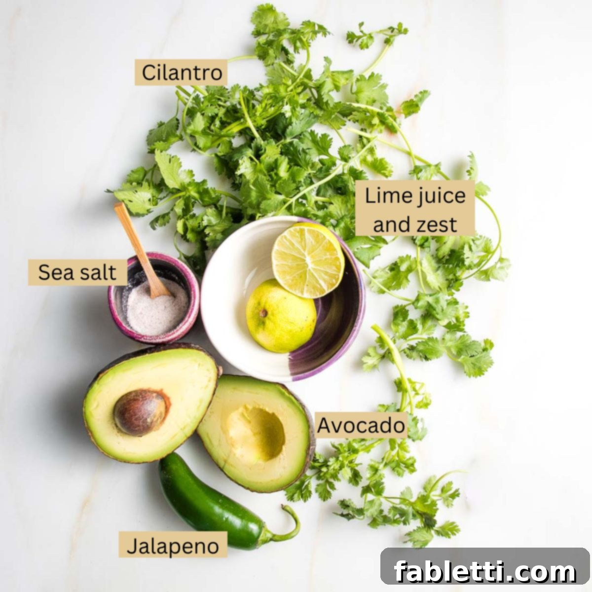 Luscious Dairy-Free Avocado Lime Dressing 3 Labeled ingredients for avocado lime dressing: fresh cilantro, ripe avocado, bright lime zest and juice, and a vibrant green jalapeno pepper, neatly arranged and ready for blending.