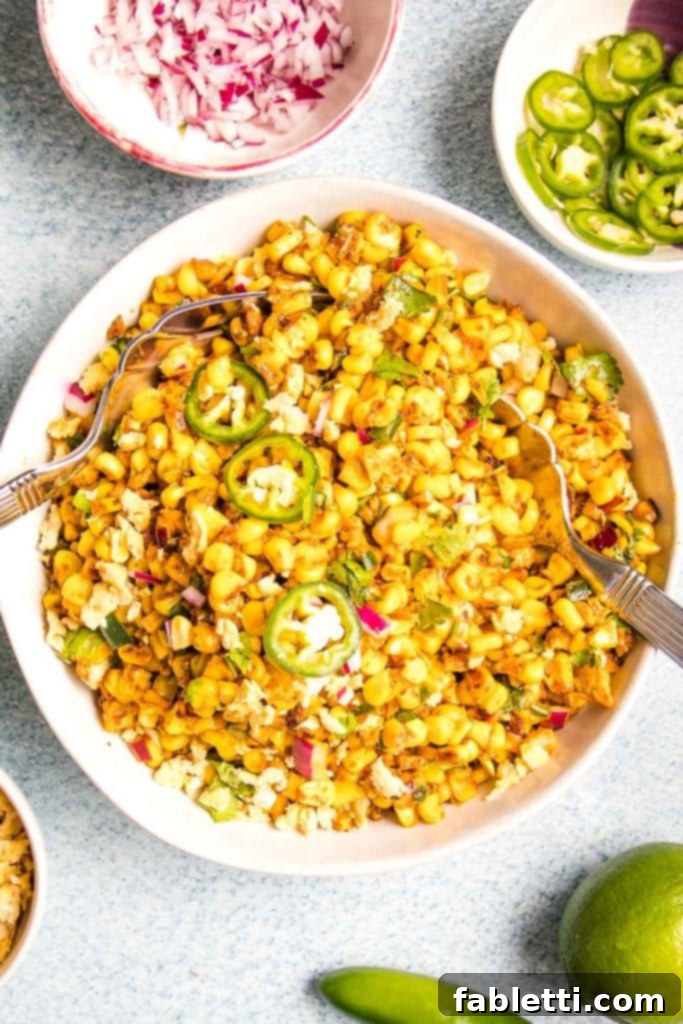 Zesty Vegan Elote 17 White bowl filled with mexican street corn salad with small bowls of extra red onion, limes, jalapenos for garnish.