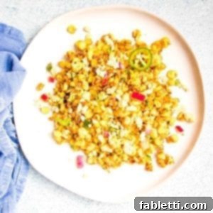 Zesty Vegan Elote 18 Mexican Street Corn Salad with red onions, jalapenos, cilantro and spices on a large white rimmed plate atop a blue napkin
