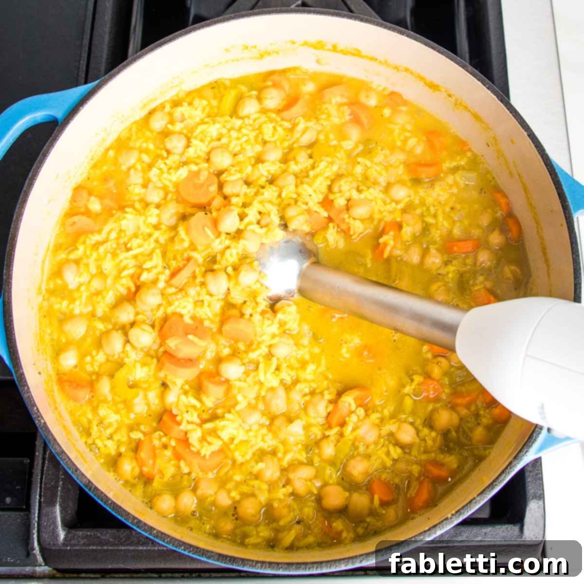 Zesty Vegan Lemon Chickpea Rice Soup 12 Dutch oven with chickpea vegetable soup and an immersion blender being used.