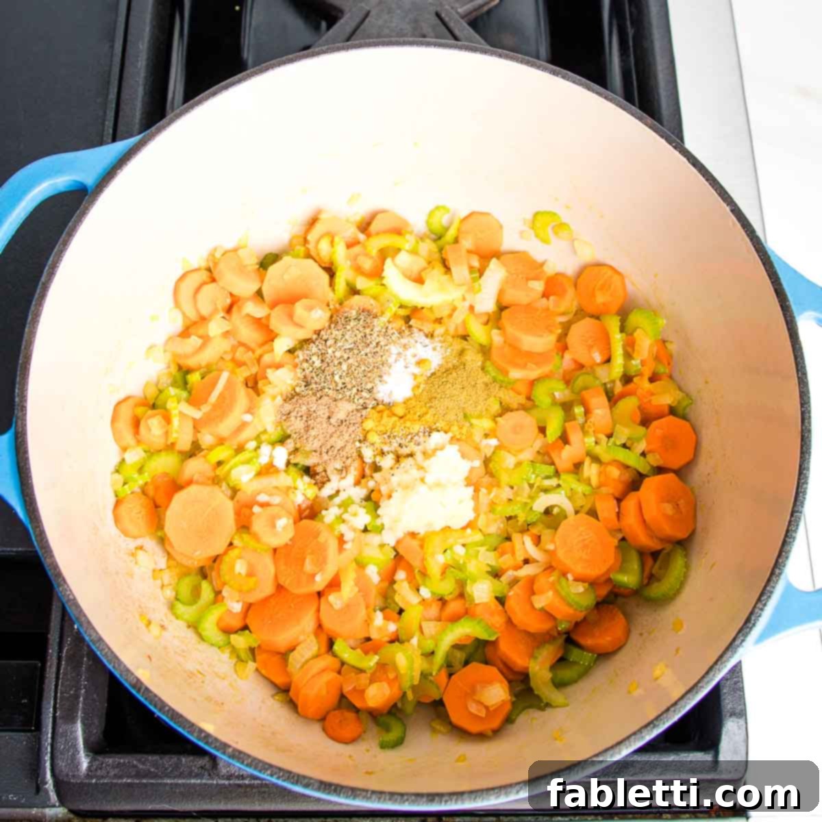 Zesty Vegan Lemon Chickpea Rice Soup 6 Dutch oven with sautéed carrots, onion, and celery, ready for spices and garlic.