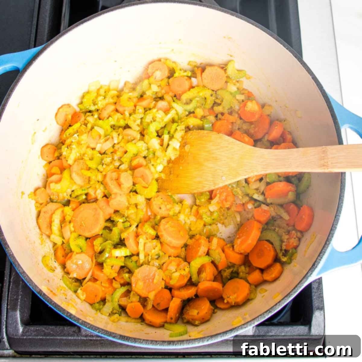 Zesty Vegan Lemon Chickpea Rice Soup 7 Dutch oven with sauteed carrots, onions, and celery with spices and garlic.
