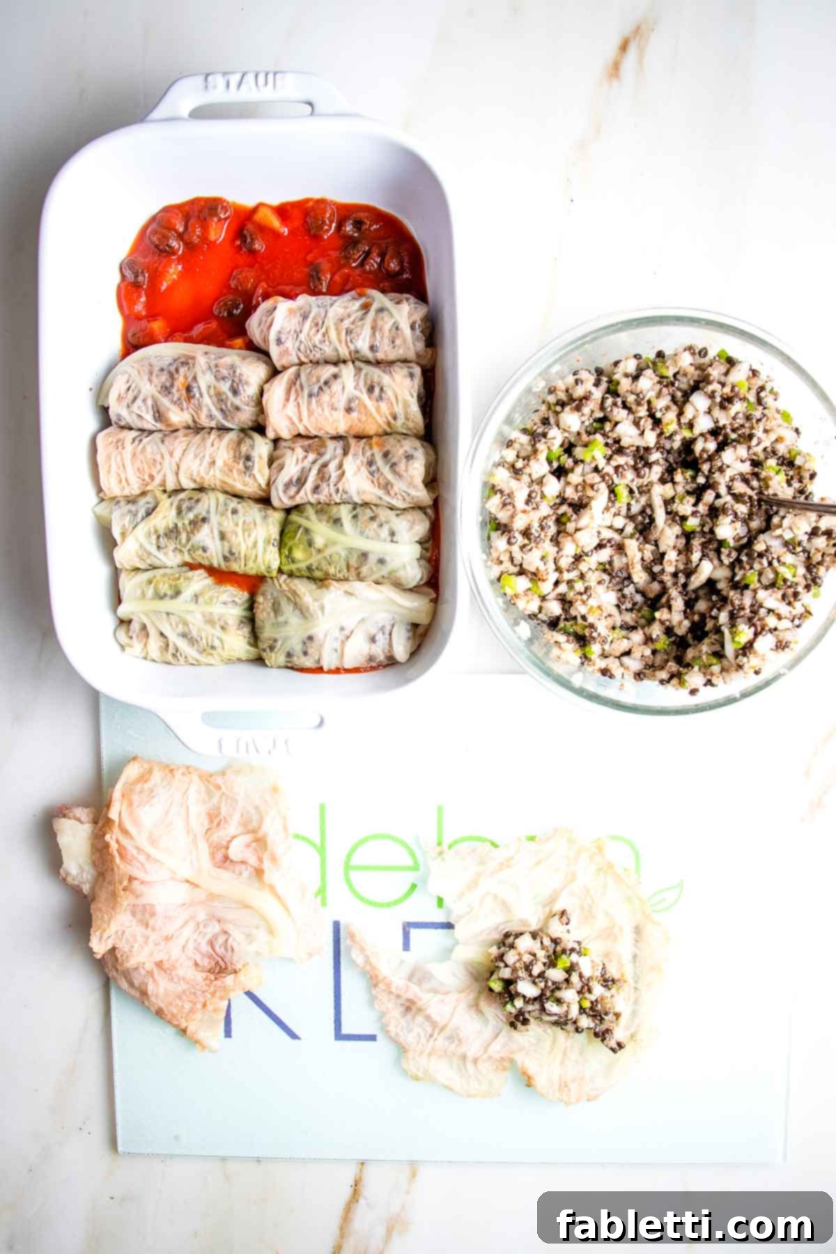 Loading cabbage rolls onto sweet and sour sauce in a baking dish.