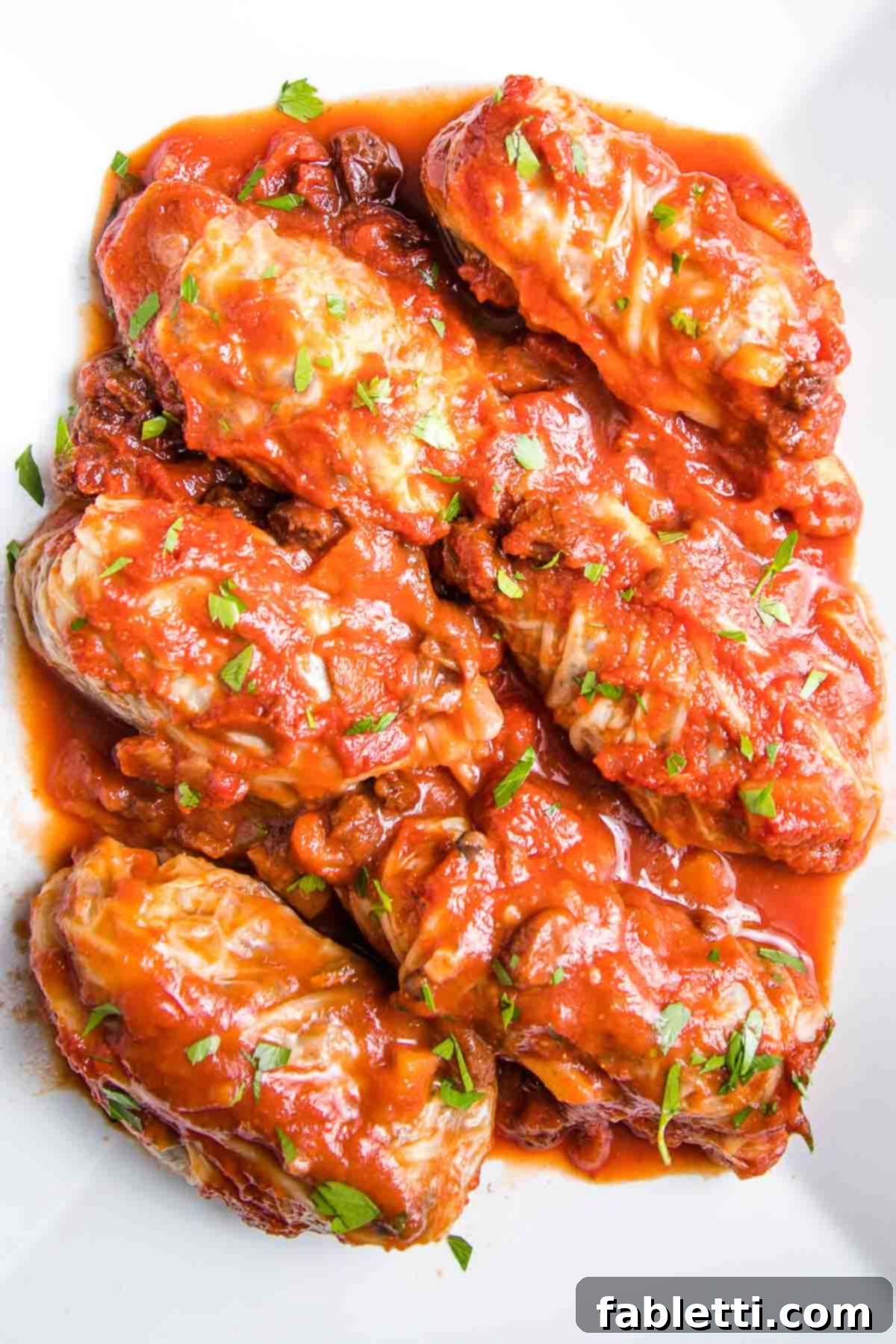 Stuffed cabbage rolls smothered in sweet and sour tomato sauce on a platter.