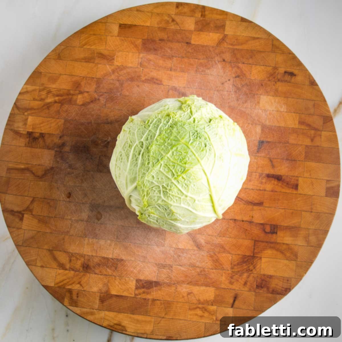 Round cutting board with a head of savory cabbage in the center.