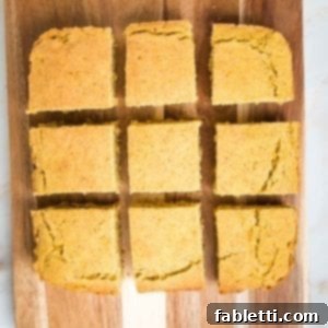 Double Corn Gluten-Free Vegan Cornbread 14 Square cornbread, on a wooden board, cut into 9 even slices, ready to serve.