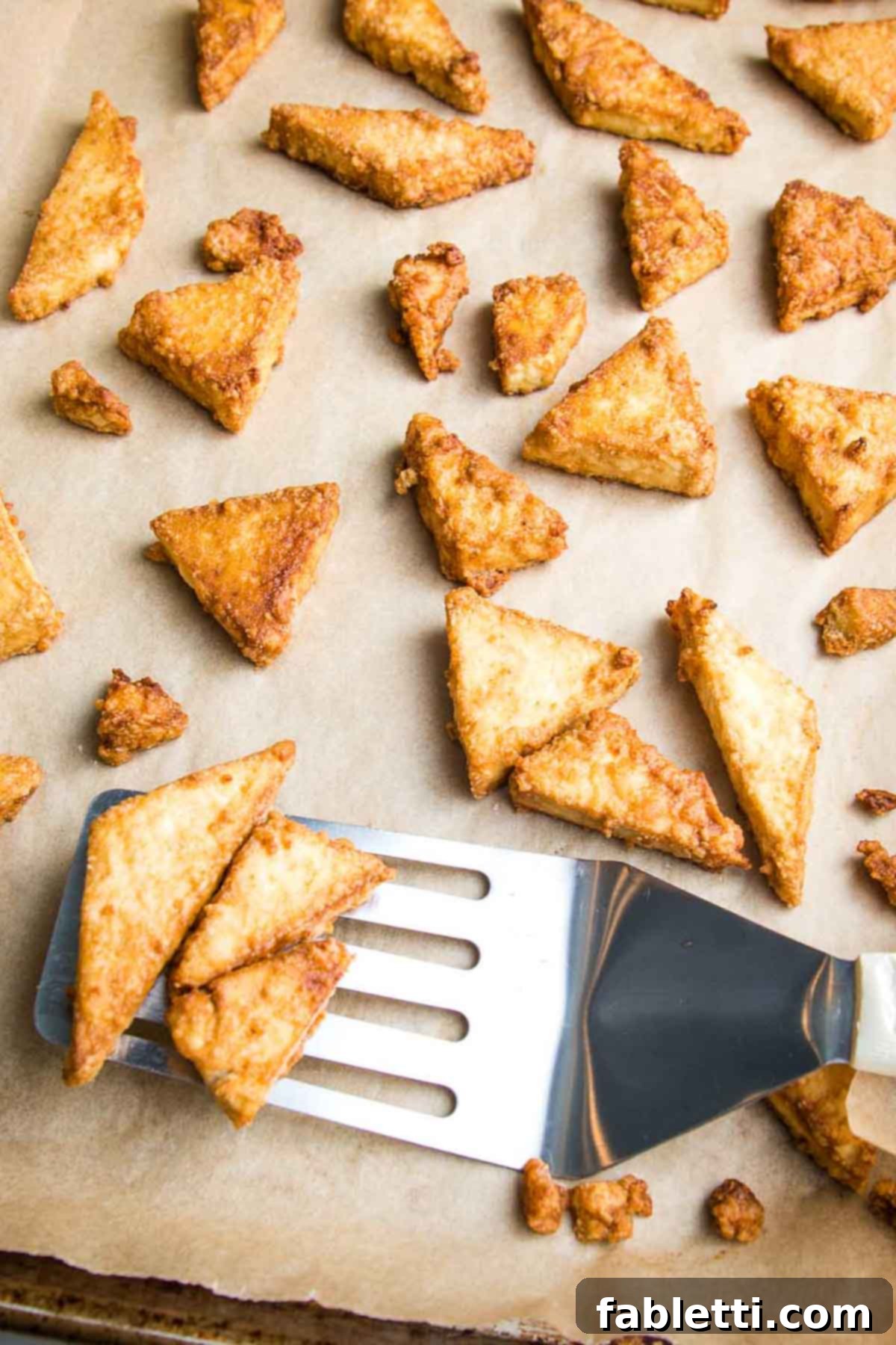Ultimate Crispy Baked Tofu 12 Crispy pieces of tofu coming off a parchment lined baking sheet.