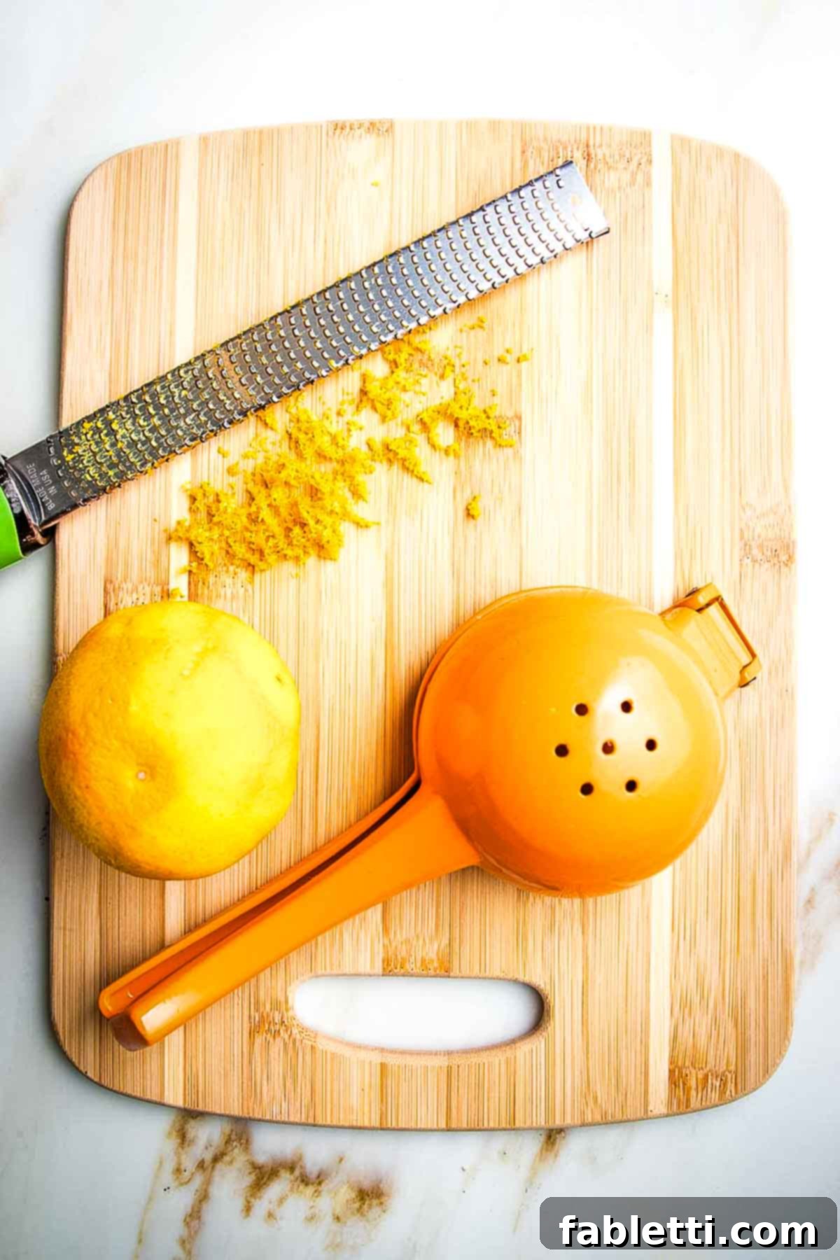 Naturally Sweetened Cranberry Chia Jam 5 Whole orange that has been zested with a microplane onto a cutting board and a citrus juicer on the side.