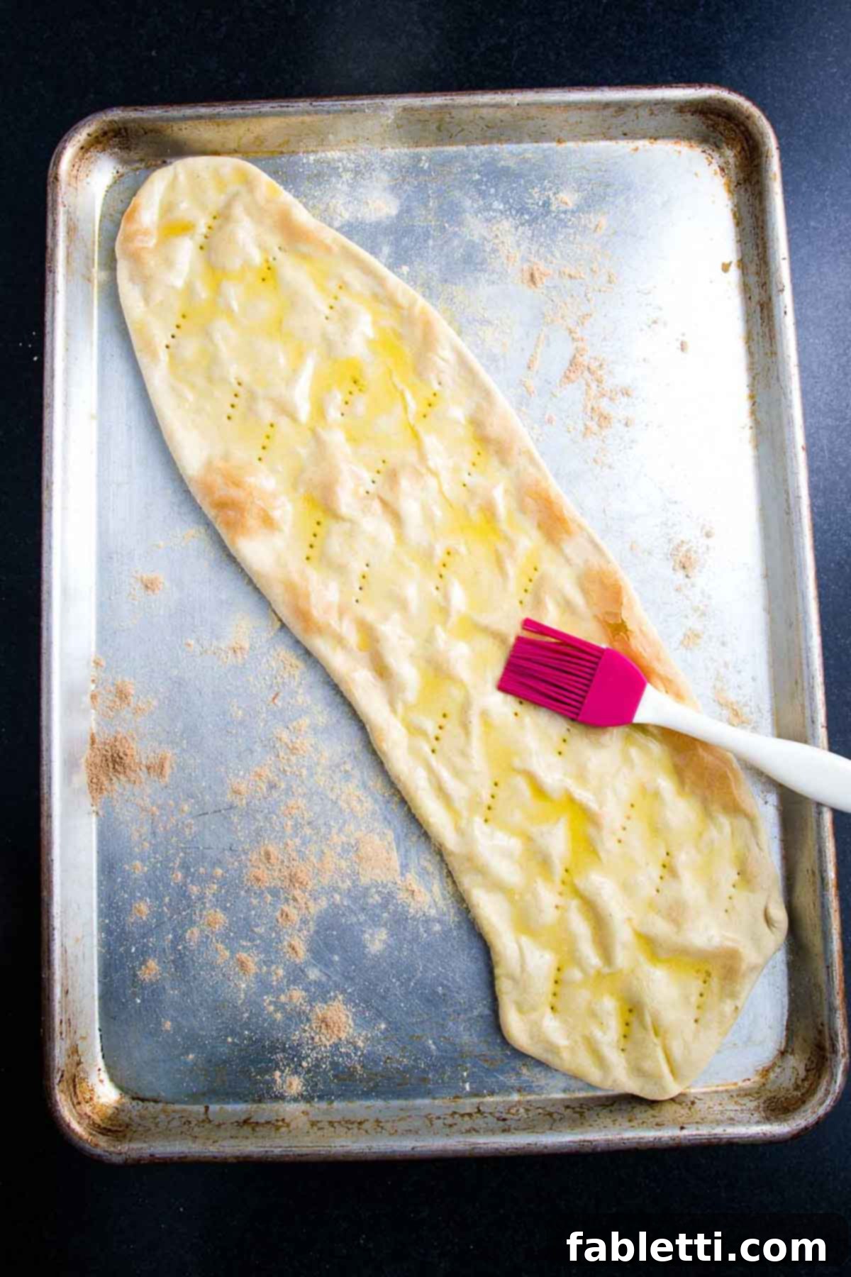 Effortless Plant-Based Flatbread 12 Brushing oil onto a flatbread crust on a baking tray.